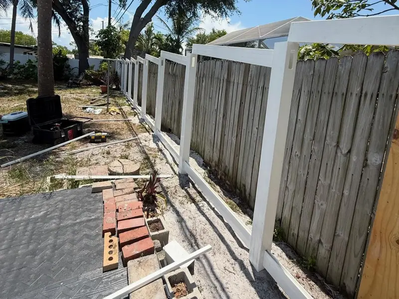 Old wood fence being replaced with new white vinyl fencing in Tampa