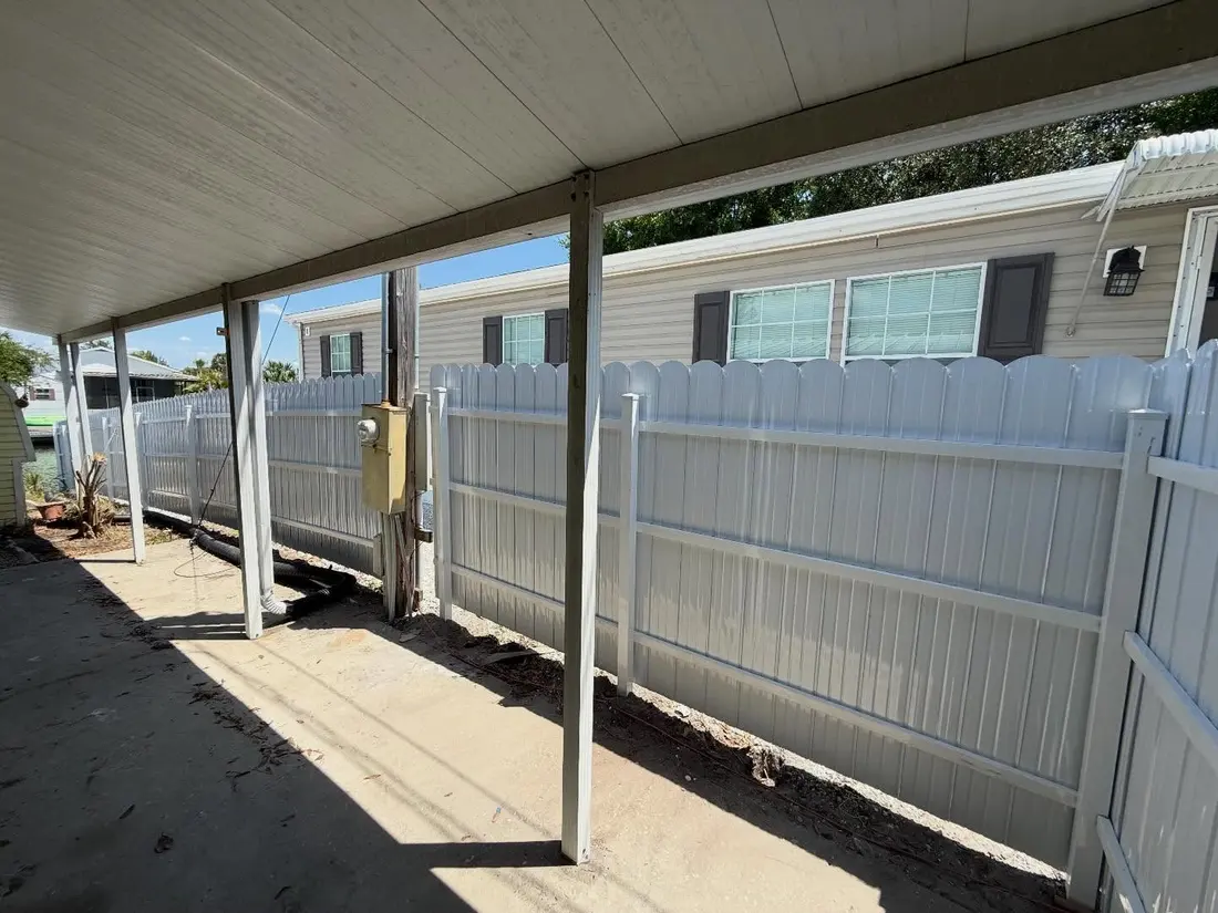 White vinyl picket fence beside a covered carport