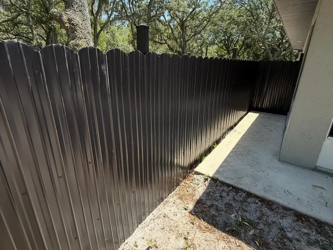 Dark scalloped-top privacy fence along a shaded side yard