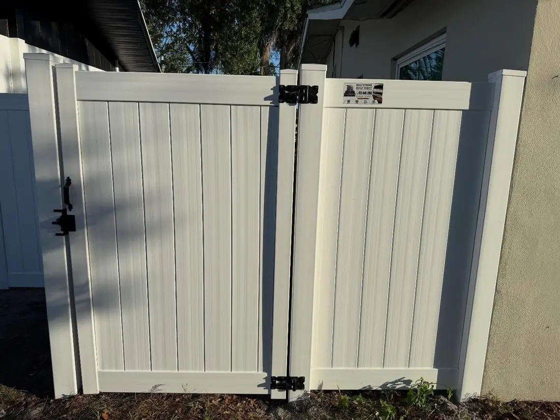 White vinyl double gate with Daimon Fence sign in Tampa