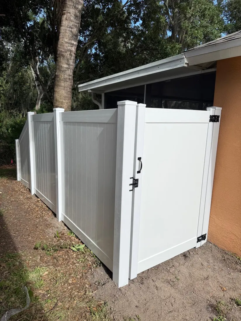White vinyl privacy fence and gate beside a stucco home